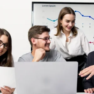 A group of people sitting around a table with laptops.