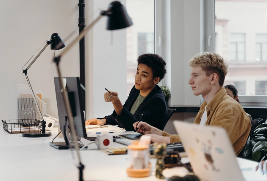 Two people sitting at a table with computers.