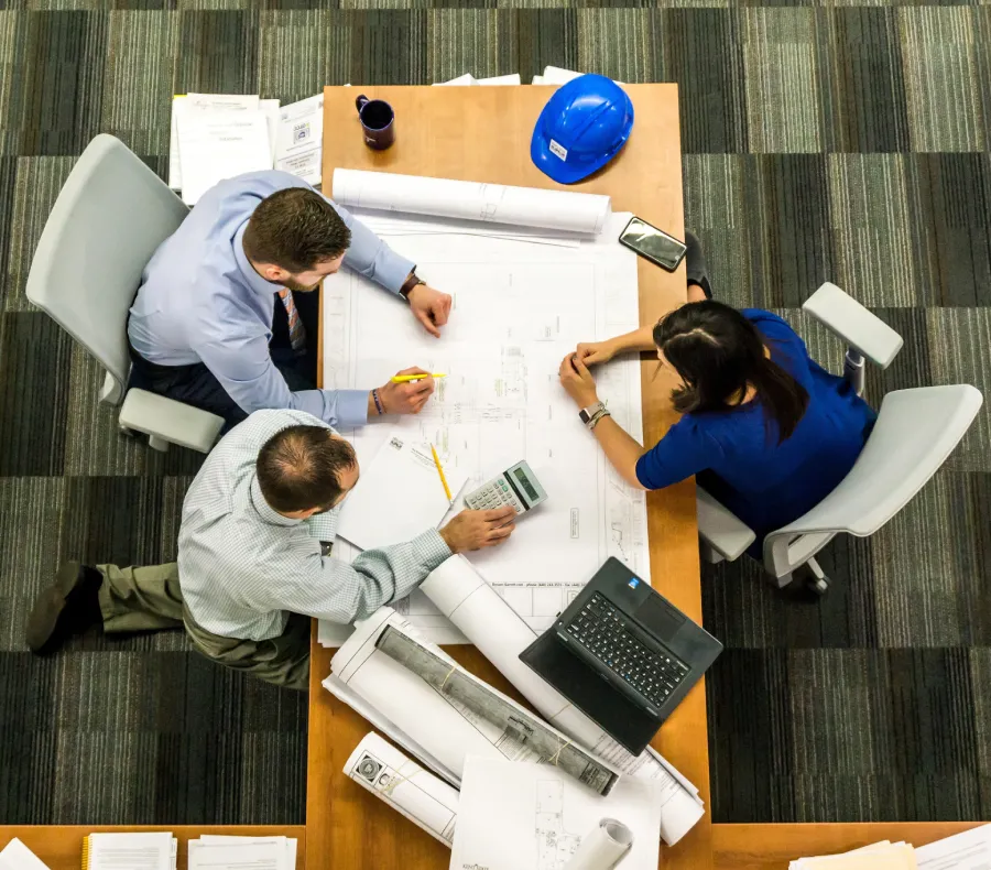 Three people sitting at a table with papers and pens.