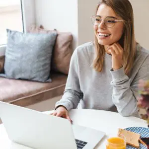 A woman sitting at a table with her laptop.